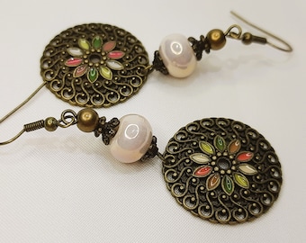 May include: A pair of bronze earrings with a filigree design and a white bead. The filigree design features a flower with colorful enamel accents.
