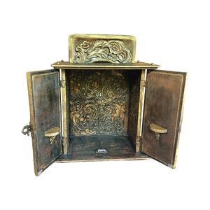 cabinet open showing plaster relief on back inner wall. inner door have small shelves that hold the two gold frames included