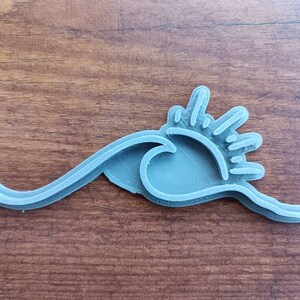 Könnte beinhalten: Ein grauer 3D-gedruckter Ausstecher in Form einer Welle mit einer aufgehenden Sonne darüber.