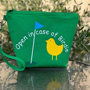 May include: Green zippered pouch with a white graphic of a golf flag and a yellow bird with the text "Open in case of Birdie".