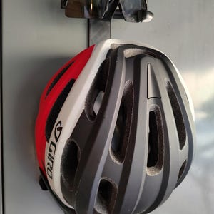 May include: A bicycle helmet with red, white, and black accents, and a pair of black sunglasses. The helmet has the brand name "GIRO" printed on the side. The sunglasses are mounted above the helmet.