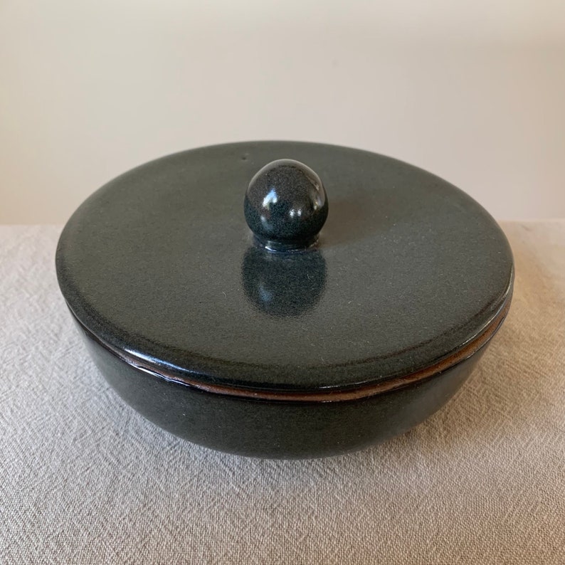 Peut inclure: Un plat en c&eacute;ramique vert fonc&eacute; avec un couvercle. Le couvercle a un bouton rond sur le dessus.