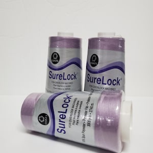 May include: Three spools of lilac-colored thread for overlock sewing machines. Each spool is labeled "SureLock" and "For Overlock Machines". The spools are 3000 yards (2740 meters) each.