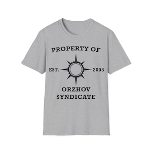 May include: A heather gray t-shirt with a crew neck. The front of the shirt features the text "PROPERTY OF" above a compass-like design with the text "EST. 2005" and "ORZHOV SYNDICATE" below.