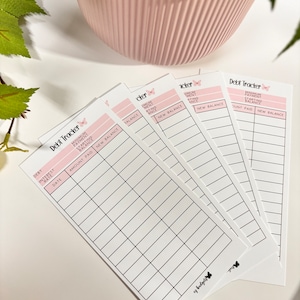 May include: Set of five white debt tracker cards with black lines and text. Each card has a butterfly graphic and the text "Debt Tracker". The cards are designed to help track debt payments, interest rates, and balances.