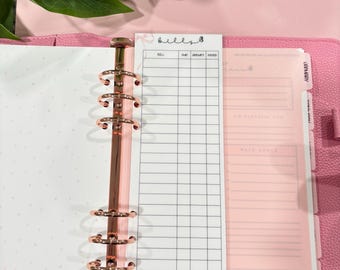 Può includere: Un'agenda rosa con un raccoglitore color oro rosa e un inserto bianco per il monitoraggio delle bollette. Il tracker delle bollette ha una griglia per tenere traccia delle bollette, delle scadenze, degli importi e se sono state pagate. Il testo "bills" è in alto.