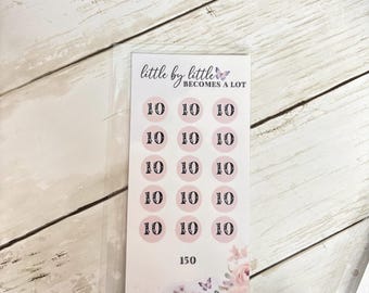 May include: A pink and white savings tracker with the text "little by little becomes a lot." The tracker has 15 circles with the number 10 inside each, totaling 150. Floral and butterfly accents are at the bottom.