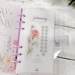 Pode incluir: Uma folha de fichário A6 translúcida para um desafio de poupança de janeiro com uma ilustração de um cravo rosa, uma lista de valores em dólares em círculos de $5 a $15 e o texto January, Savings Challenge e Birth Flower Carnation.