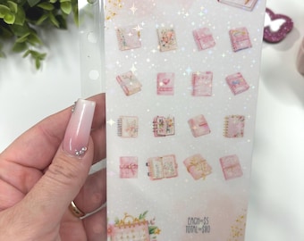 May include: A clear plastic sheet with the text "Planner Supplies" and illustrations of pink notebooks and a calendar. The sheet is held by a hand with a long, light pink nail. The background is white with gold glitter.