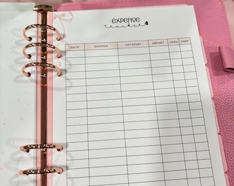 Puede incluir: Agenda rosa con herrajes de oro rosa y una hoja de seguimiento de gastos. El rastreador de gastos tiene columnas para la fecha, el gasto, la categoría, la cantidad, el efectivo y la tarjeta. Las palabras "expense tracker" están escritas en la parte superior de la página.