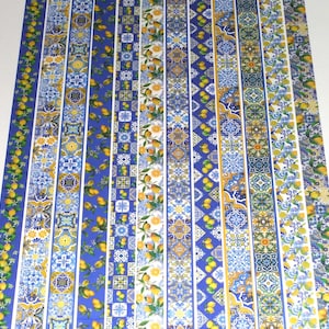 May include: A fabric with a repeating pattern of blue, yellow, and white stripes. The stripes feature a variety of geometric designs, including lemons, flowers, and tiles.