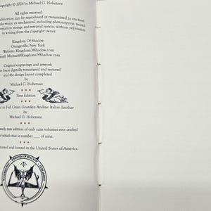 May include: An open book showing text including copyright details, author's name, and publisher information. The text mentions "Kingdom Of Shadow" and "First Edition." The book is described as hand-bound in Italian leather. A circular emblem is at the bottom.
