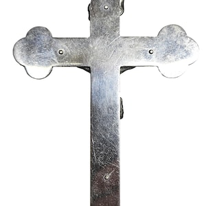 Puede incluir: Un crucifijo plateado con un dise&ntilde;o detallado. La cruz presenta bordes redondeados y una peque&ntilde;a figura de Jes&uacute;s. La parte superior tiene un lazo para colgar. El metal tiene una apariencia ligeramente envejecida.