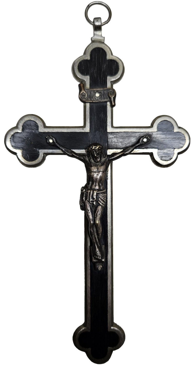 Puede incluir: Un crucifijo decorativo con una cruz de madera oscura y un marco de metal plateado. La figura de Jes&uacute;s es de color bronce. La cruz tiene un lazo en la parte superior para colgar.
