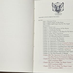 May include: An open book displaying the contents page of "THE KEY OF SOLOMON THE KING". The contents include chapters on planetary hours, divine love, and conjurations. A bird graphic is at the top.