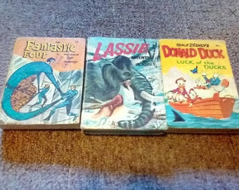 May include: Three vintage comic books, one featuring the Fantastic Four, another with Lassie, and the third with Donald Duck. The Fantastic Four comic has a blue and yellow cover with the title "Fantastic Four" in bold letters. The Lassie comic has a brown and green cover with the title "Lassie" in bold letters. The Donald Duck comic has a yellow and blue cover with the title "Donald Duck" in bold letters.