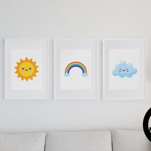 Puede incluir: Tres impresiones enmarcadas blancas con lindas ilustraciones de dibujos animados de un sol amarillo, un arcoíris y una nube azul. Cada ilustración tiene una cara sonriente.