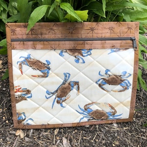 May include: A brown zippered pouch with a white quilted fabric interior featuring a repeating pattern of blue crabs. The pouch has a brown fabric border.