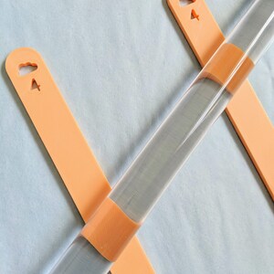 May include: Two orange rolling pins with cloud and airplane cutouts. The rolling pins are made of clear acrylic and have a textured surface.