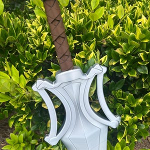 Puede incluir: Una espada de color plateado con una guarda ancha y angular y un pomo. El mango est&aacute; envuelto en material marr&oacute;n con un patr&oacute;n entrecruzado. La hoja es ancha y se estrecha hacia la punta, mostrando un acabado met&aacute;lico liso en todo el cuerpo.