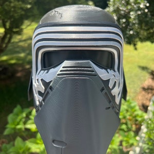 Peut inclure: Un casque imprim&eacute; en 3D noir et argent avec une visi&egrave;re et une surface textur&eacute;e. Le casque est con&ccedil;u pour ressembler &agrave; un personnage d'un film de science-fiction.