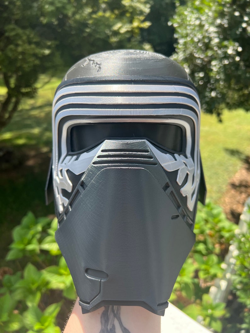 Peut inclure: Un casque imprim&eacute; en 3D noir et argent avec une visi&egrave;re et une surface textur&eacute;e. Le casque est con&ccedil;u pour ressembler &agrave; un personnage d'un film de science-fiction.
