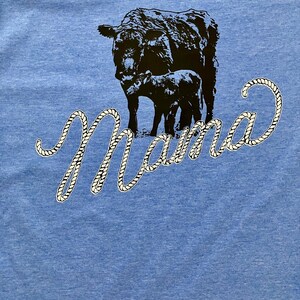May include: A blue t-shirt with a black cow and calf silhouette and the word "Mama" in a white rope design.