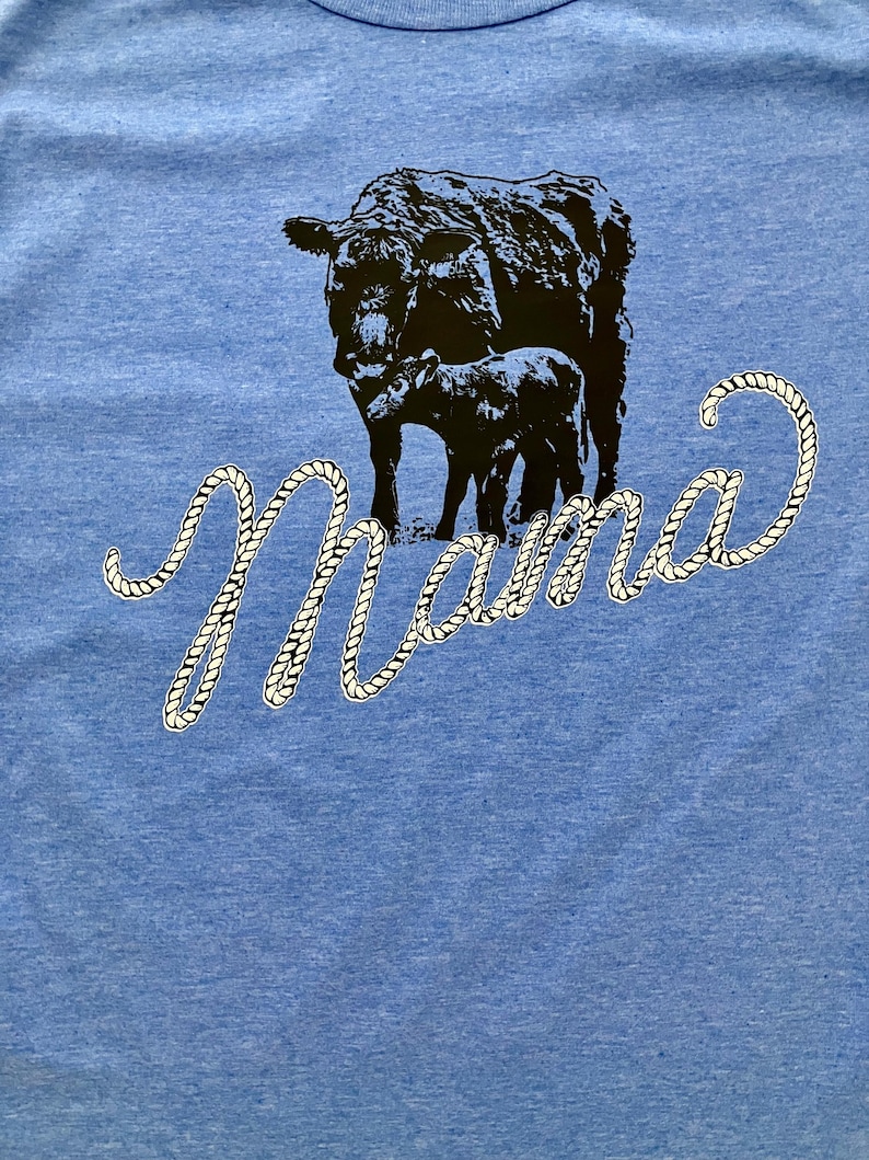 May include: A blue t-shirt with a black cow and calf silhouette and the word "Mama" in a white rope design.