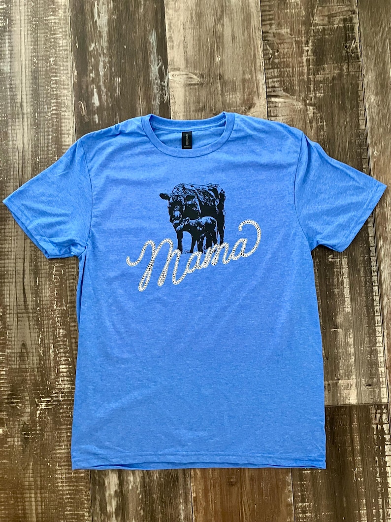 May include: A light blue t-shirt with a black silhouette of a cow and calf with the word "Mama" in rhinestones.