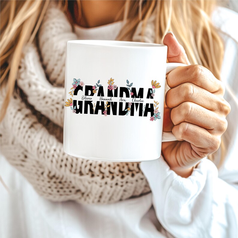 May include: White ceramic mug with the word "Grandma" in black letters surrounded by colorful flowers. The names "Oliver", "Hannah", "Ava", and "Charlie" are written in smaller letters above the word "Grandma".
