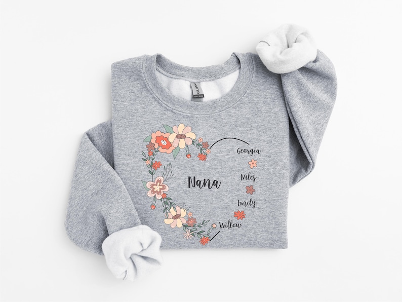 Pode incluir: Camisola cinzenta com um design de cora&ccedil;&atilde;o floral que diz "Nana" e os nomes Georgia, Miles, Emily e Willow.
