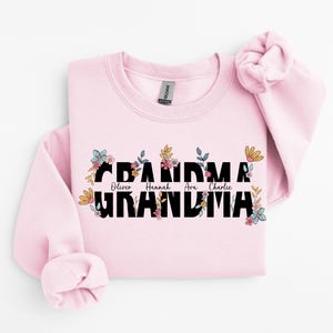 May include: Pink sweatshirt with a floral design and the text "Grandma" with the names "Oliver, Hannah, Ava, Charlie" printed above the word "Grandma".