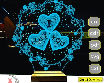 May include: A blue LED lamp with a floral design and three heart-shaped elements that read "I LOVE YOU". The lamp sits on a wooden base. The text "LACY 3D LAMP" is at the top.