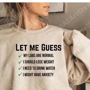 May include: Beige sweatshirt with the text "LET ME GUESS" and a list of relatable statements. The statements include "MY LABS ARE NORMAL", "I SHOULD LOSE WEIGHT", "I NEED TO DRINK WATER", and "I MIGHT HAVE ANXIETY".