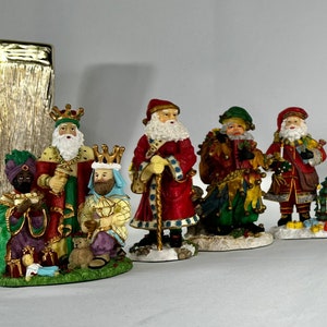 May include: A collection of Christmas figurines featuring Santa Claus and the Three Wise Men. The figurines are painted in vibrant colors, with detailed clothing and accessories. The set includes a small Christmas tree and gifts.