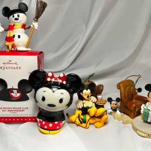 May include: A collection of Disney-themed Christmas ornaments. Includes a snowman with a broom, Minnie Mouse, Mickey Mouse, and Pluto figurines. Also includes a Hallmark Keepsake box with a Mickey Mouse Club design.