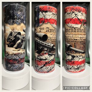 Pode incluir: Um copo de aço inoxidável com um design de bandeira americana desbotada e um rifle com o texto "2nd Amendment" e o texto da Segunda Emenda.