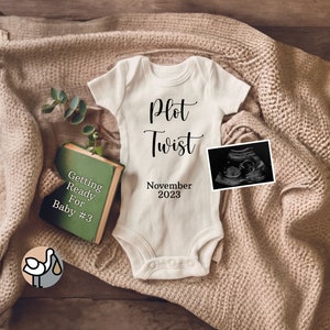 May include: A white baby onesie with the text "Plot Twist" and "November 2023". A green book with the text "Getting Ready For Baby #3" is next to the onesie. A black and white ultrasound image is on the right side of the onesie. A white stork with a baby in its beak is in the lower left corner of the image.
