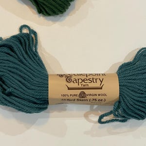 May include: A skein of teal blue tapestry yarn, labeled "Needlepoint Tapestry Yarn", "100% Pure Virgin Wool", and "40-Yard Skein (.75 oz.)".