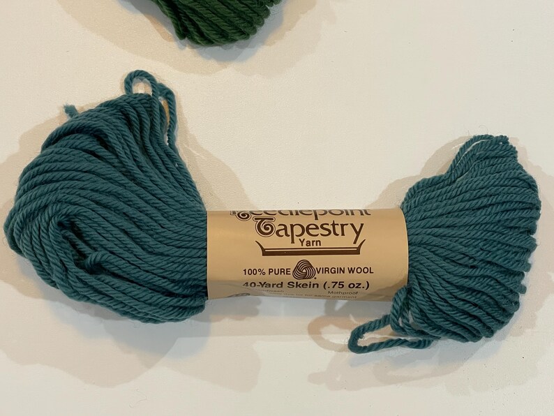 May include: A skein of teal blue tapestry yarn, labeled "Needlepoint Tapestry Yarn", "100% Pure Virgin Wool", and "40-Yard Skein (.75 oz.)".