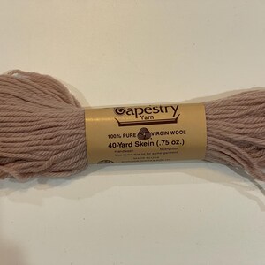 May include: A skein of Tapestry Yarn in a muted rose color. The label reads "100% Pure Virgin Wool, 40-Yard Skein (.75 oz.)". The yarn is hand dyed and mothproof. Ideal for knitting and crochet projects.