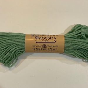May include: A skein of green tapestry yarn with a brown label. The label reads "Tapestry Yarn" and "100% Pure Virgin Wool, 40-Yard Skein (.75 oz.)". The yarn is a soft, muted green color.