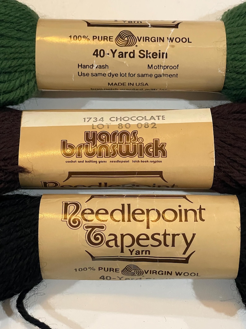 May include: Three skeins of 100% pure virgin wool yarn. The skeins are labeled "40-Yard Skein", "yarns. brunswick", and "Reedlepoint Tapestry Yarn".