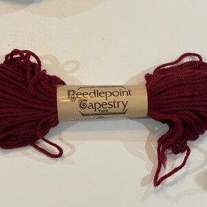 May include: A skein of deep red needlepoint tapestry yarn. The label reads "Needlepoint Tapestry Yarn".