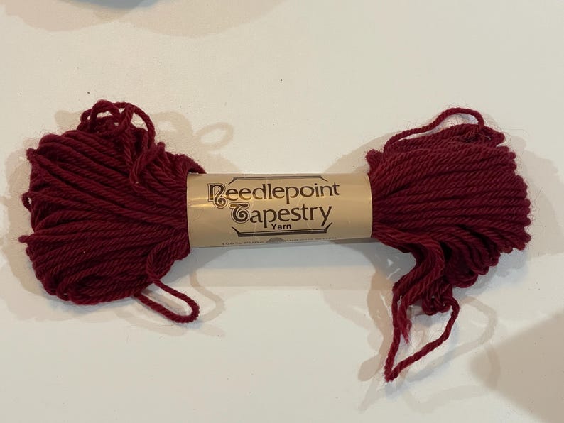 May include: A skein of deep red needlepoint tapestry yarn. The label reads "Needlepoint Tapestry Yarn".