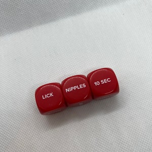 May include: Three red dice with white lettering. The dice read "LICK", "NIPPLES", and "10 SEC".