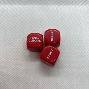May include: Three red dice with white text. The dice read "Penis/Clitoris", "Nibble", and "30 Sec".