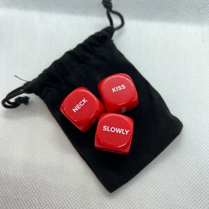 May include: Three red dice with white lettering in a black drawstring bag. The dice read "Kiss", "Neck", and "Slowly".