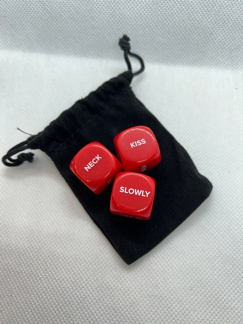 May include: Three red dice with white lettering in a black drawstring bag. The dice read "Kiss", "Neck", and "Slowly".