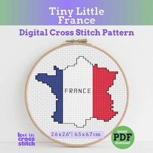 May include: A cross-stitch pattern of the French flag in a wooden embroidery hoop. The design is in the shape of France, with blue, white, and red sections. The text "FRANCE" is in the center. The pattern is 6.5 x 6.7 cm.